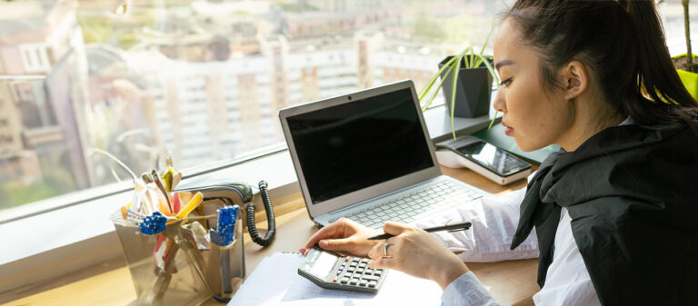 woman working on laptop using calculator