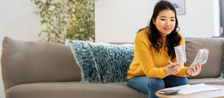 woman sitting on couch looking at bills