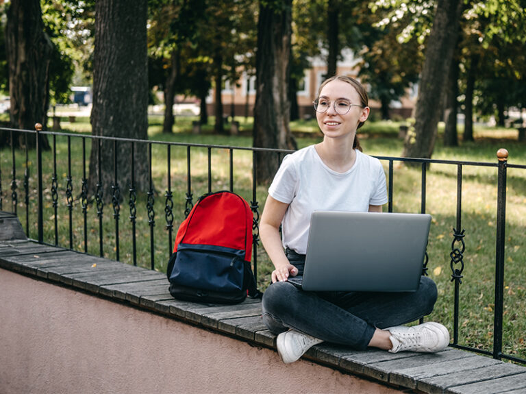 woman sitting on wall studying