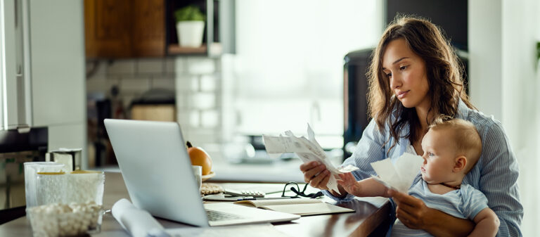 woman holding baby looking at bills